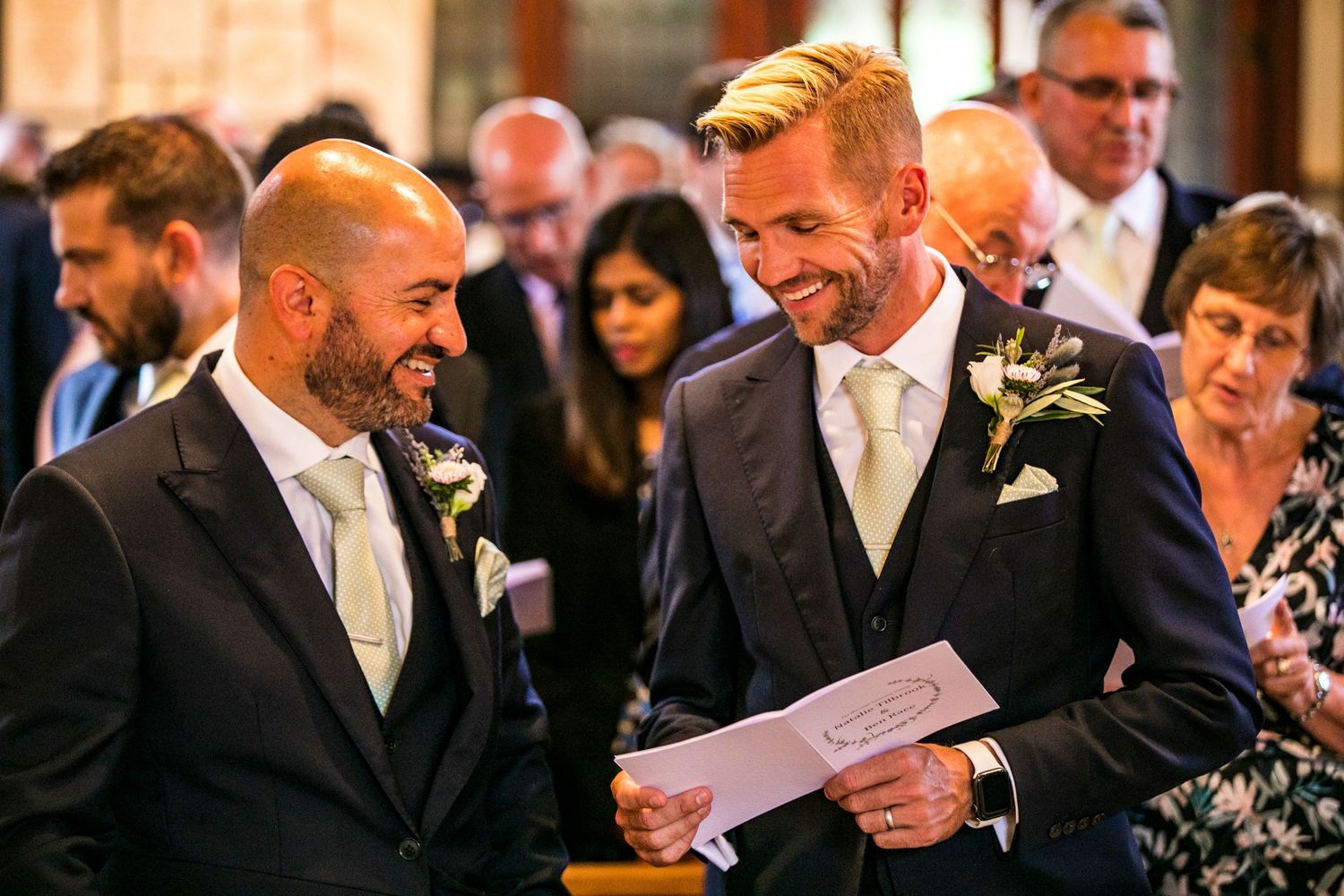 Wedding guests smile and laugh during indoor reception.