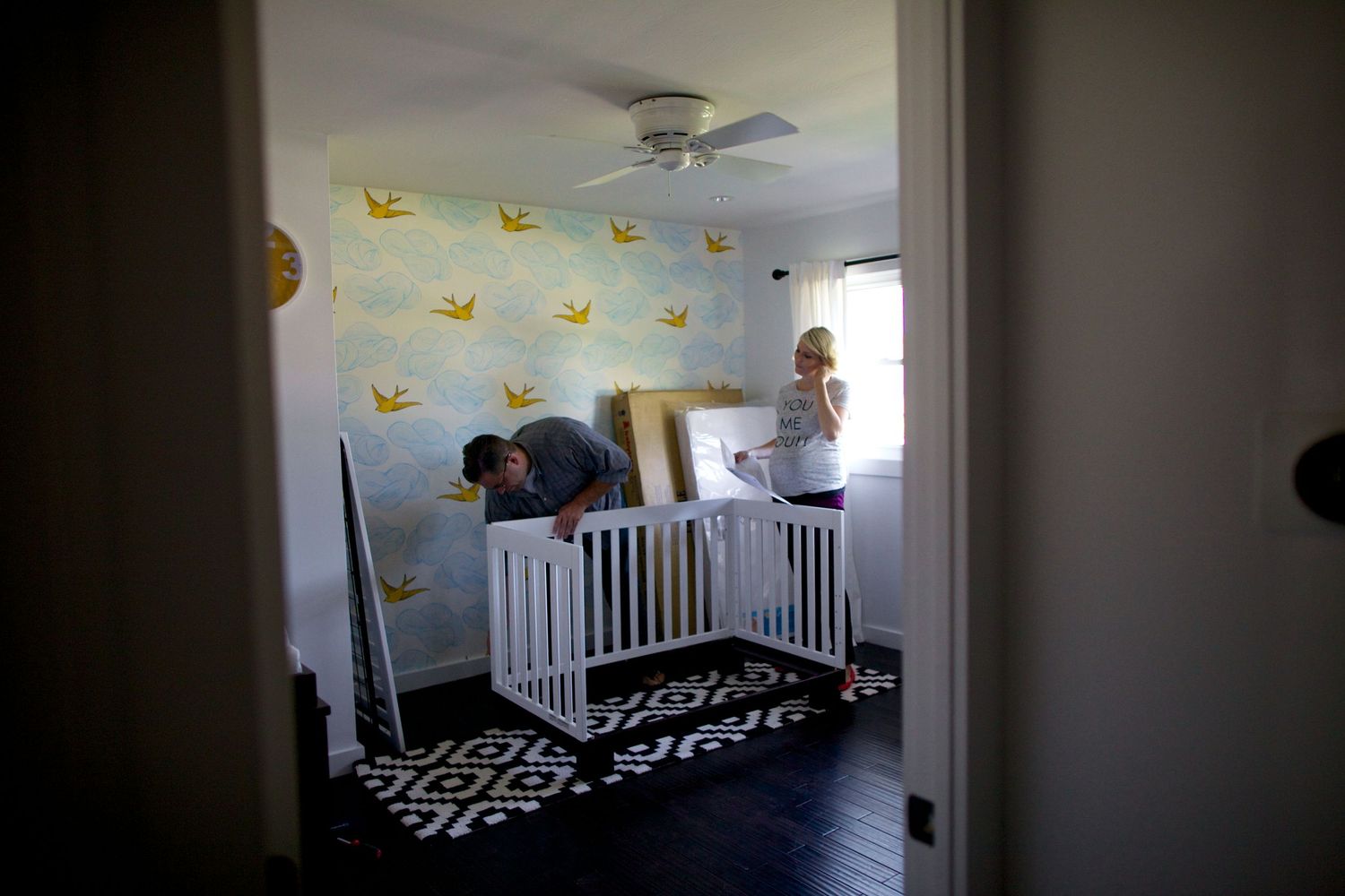 Nursery room with black and white decor featuring yellow bird wallpaper accents.