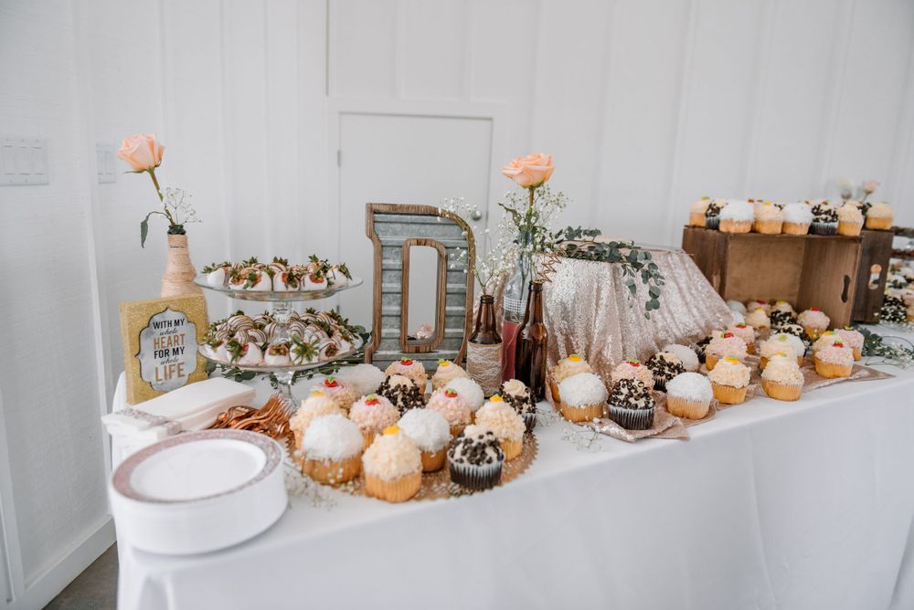Elegant dessert table with cupcakes and decorative elements in soft peach and white tones.