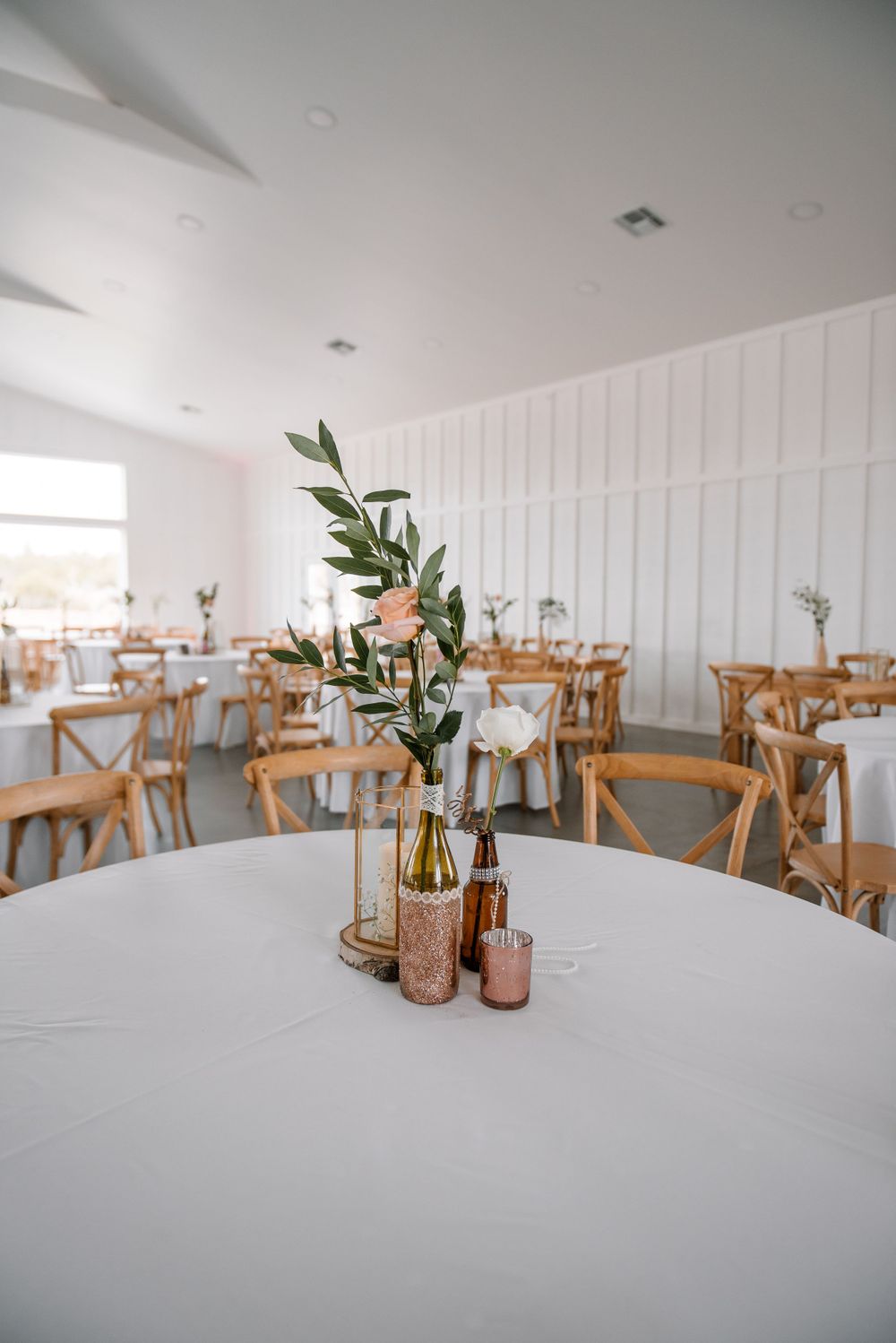 Clean white reception space with wooden chairs and minimalist table settings.