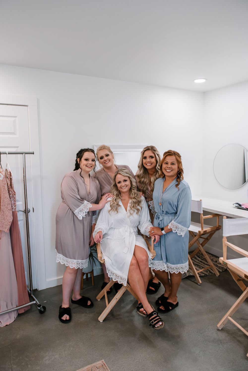 Wedding preparation scene in a bright white dressing room with pastel colored robes.