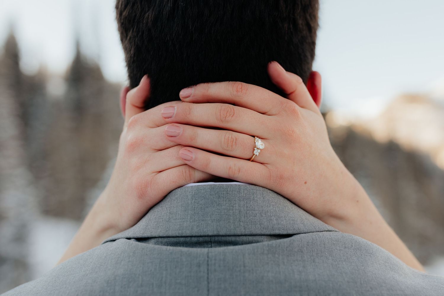 Bride holding back of grooms neck showing wedding ring