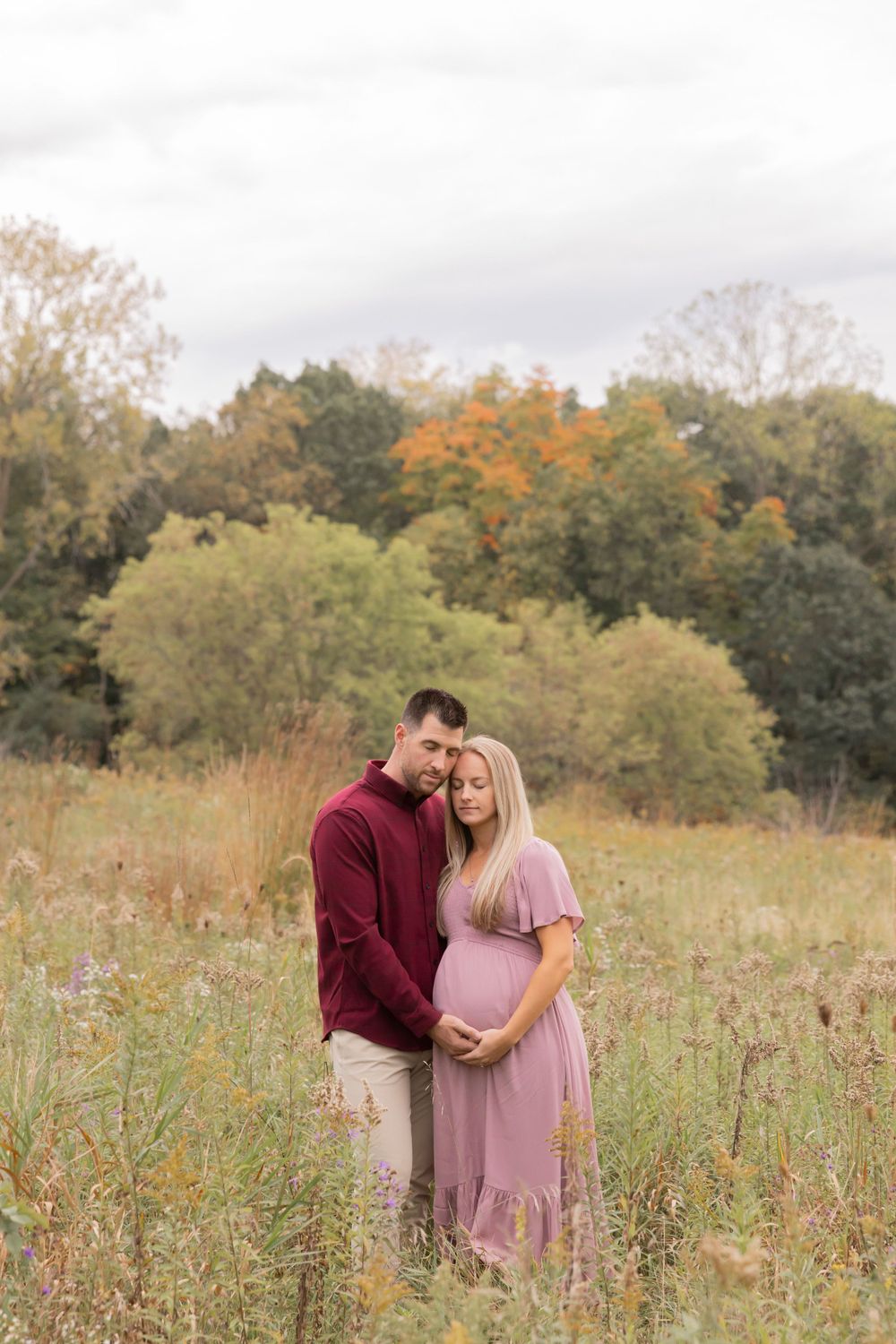 pregnant couple holding their baby bump in a field in oakland