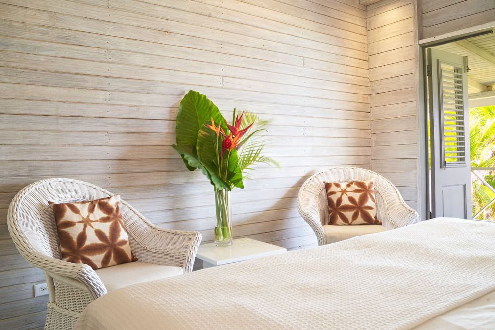 Cozy bedroom with white wicker furniture, tropical decor, and natural wood ceiling.