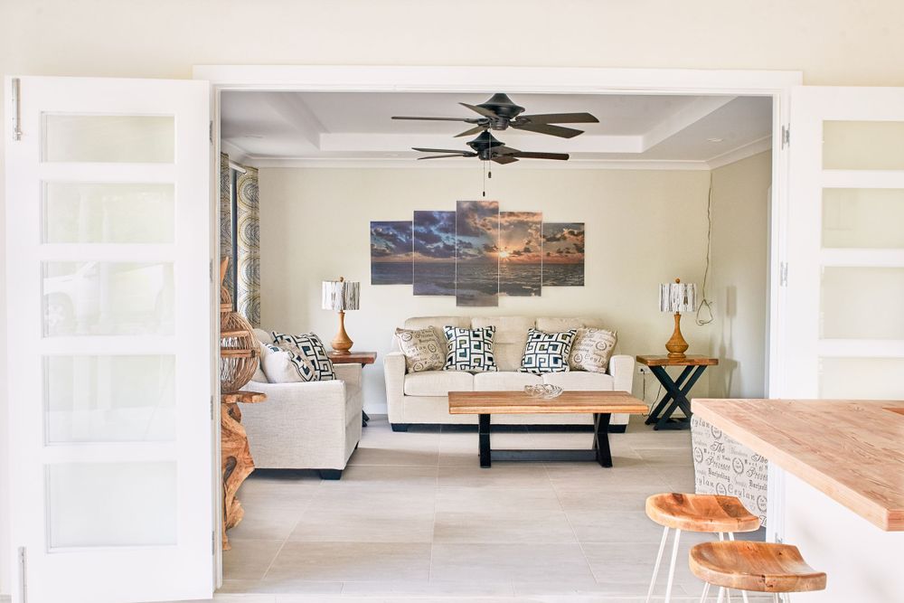 Modern living space with white walls, ceiling fans and comfortable seating arrangements.
