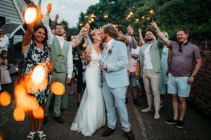 Wedding celebration at dusk with sparklers and guests lining pathway.