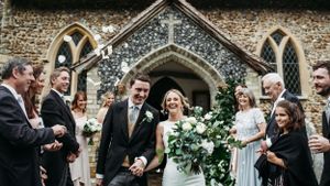 Wedding celebration outside stone church with guests throwing confetti.