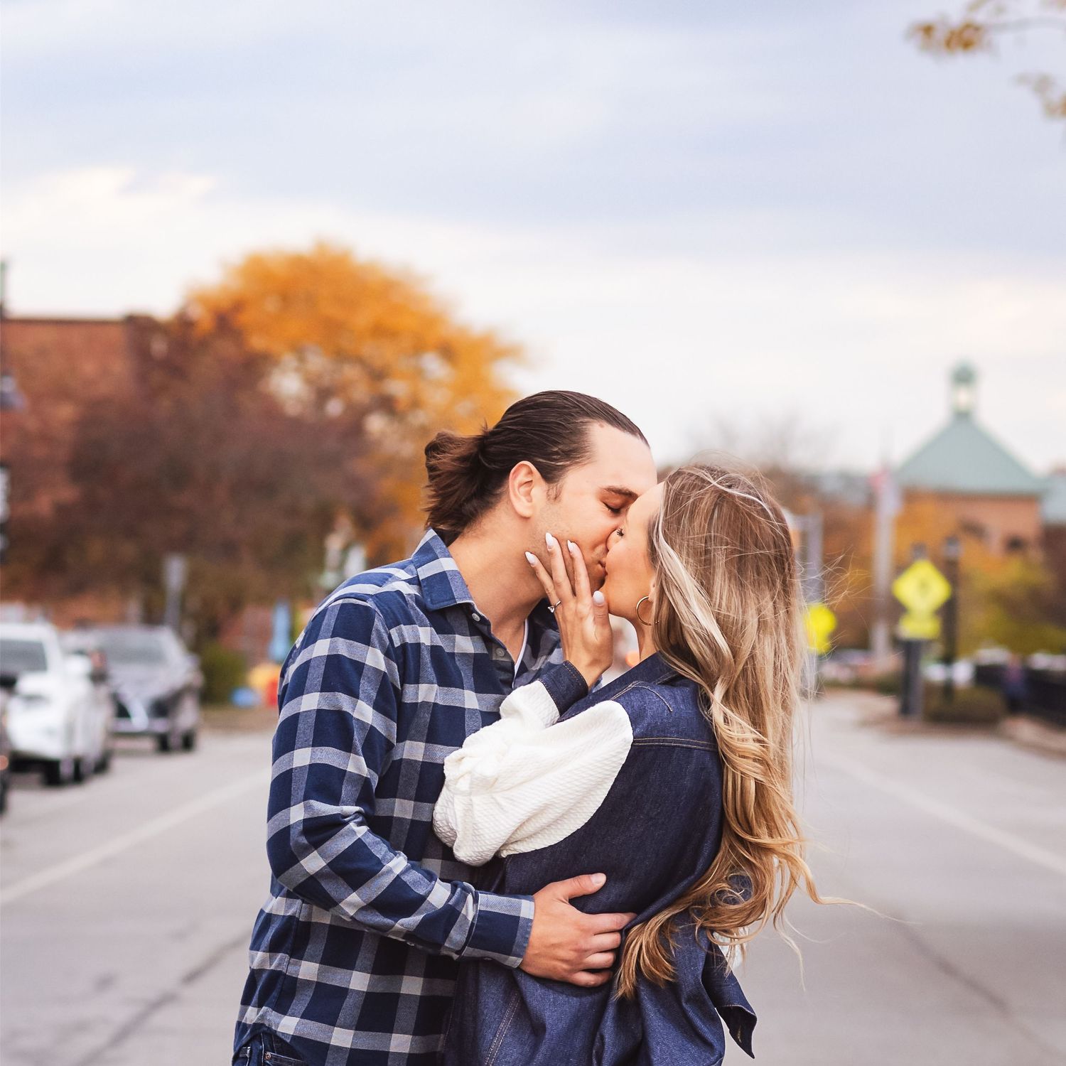 young couple kiss in middle of street with fall colors
