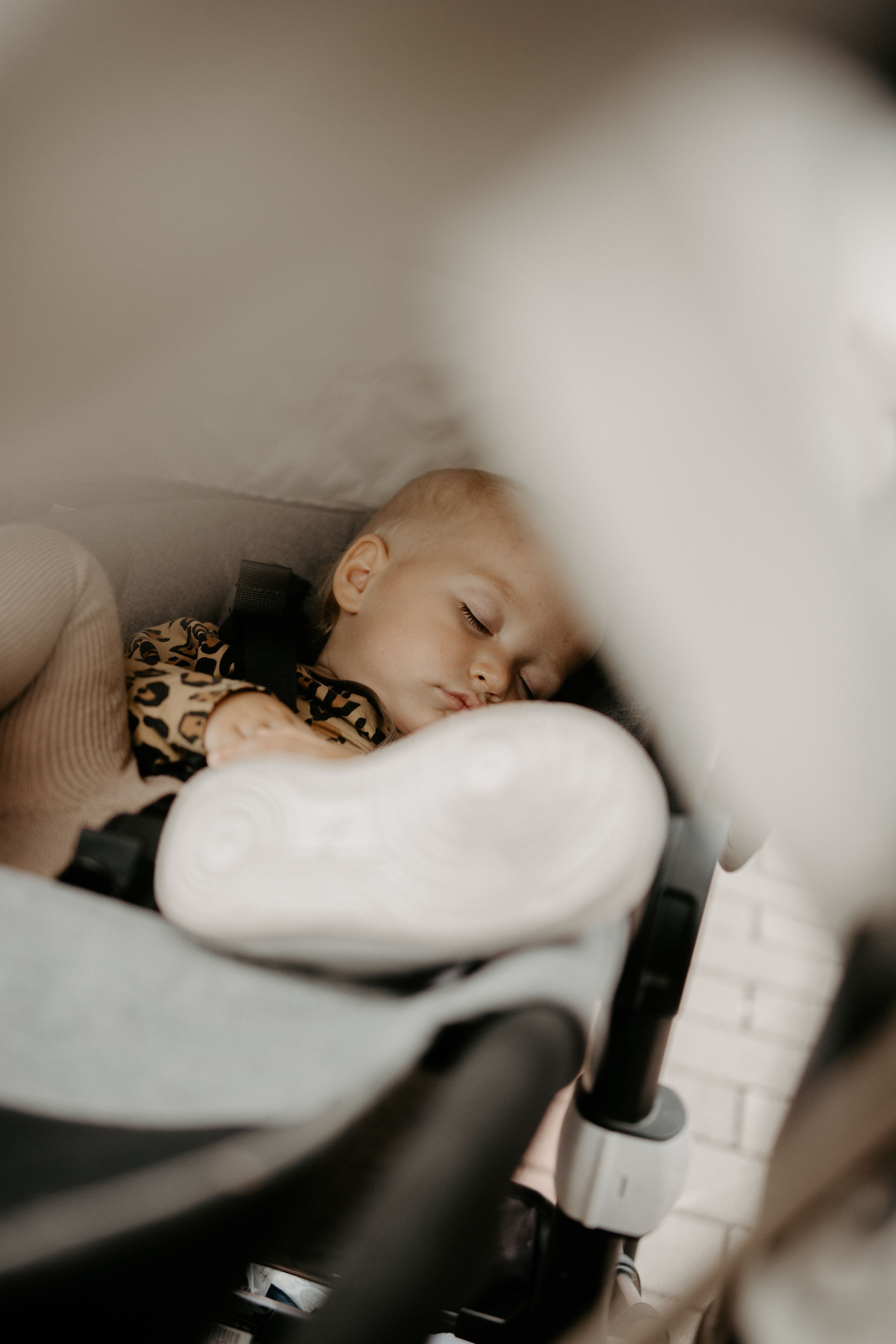Close-up of a sleeping infant nestled in a cozy white car seat.