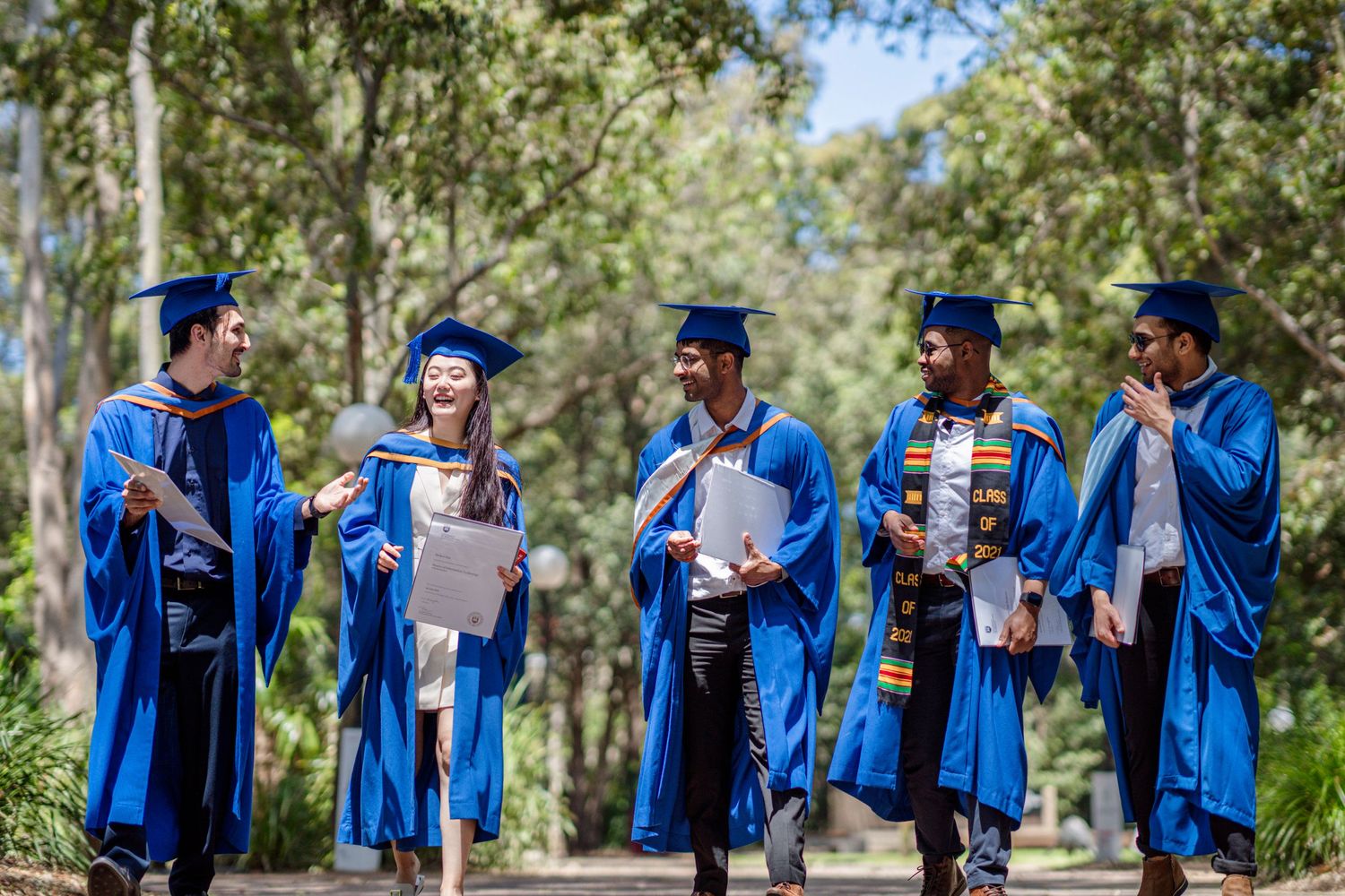 Students in graduation attire gather outdoors for candid photo session.