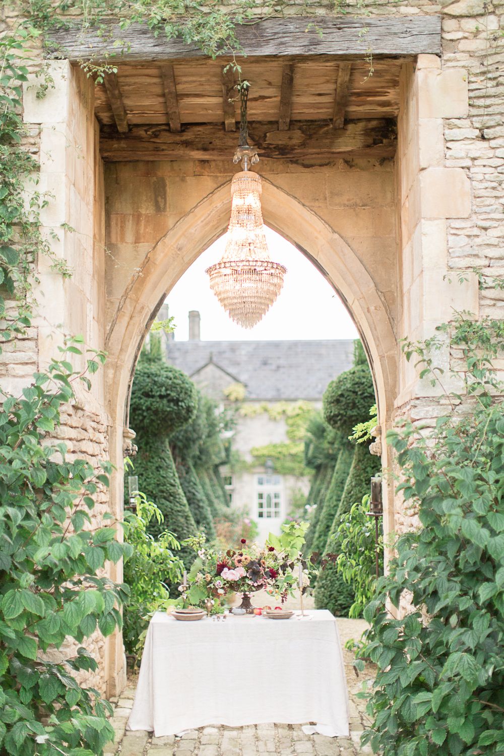 Elegant garden archway with crystal chandelier and white table setting surrounded by lush greenery at a romantic venue euridge manor