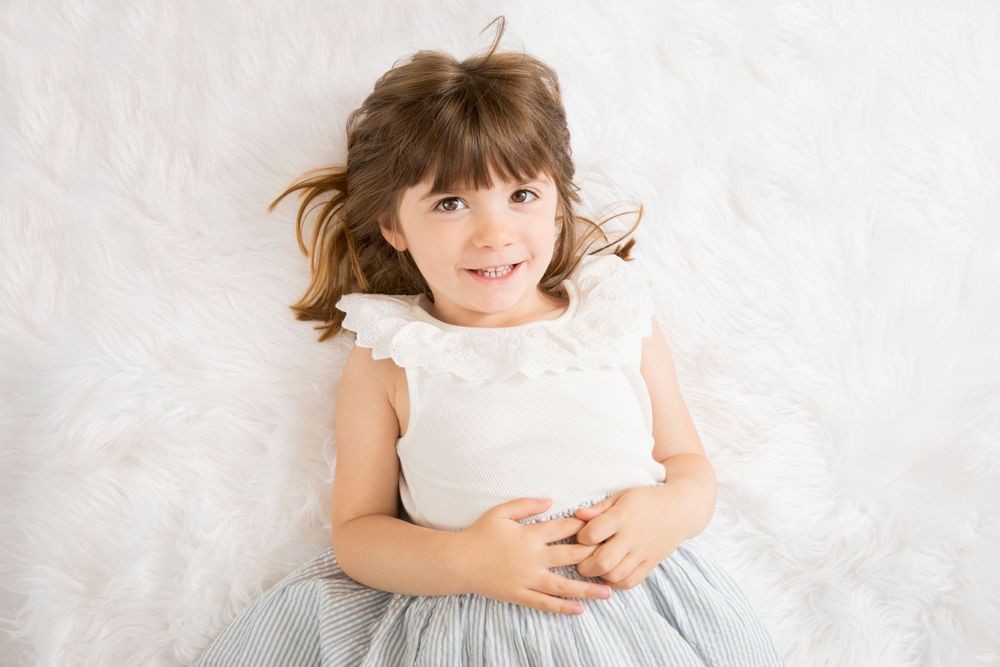 Toddler led on white flokati rug.