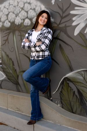 Casual portrait session against decorative wall mural wearing plaid and denim.