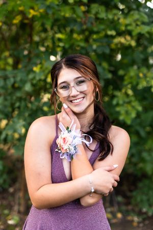 Portrait of person in purple dress outdoors with natural greenery background.