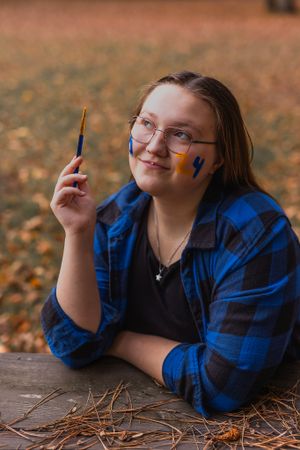 Person in blue plaid flannel sitting at wooden table with fall leaves.