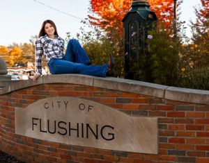 Outdoor portraits taken on brick wall with autumn trees and 'Flushing' text visible.