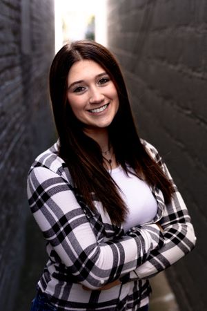 Person wearing black and white plaid flannel shirt poses against dark wall.