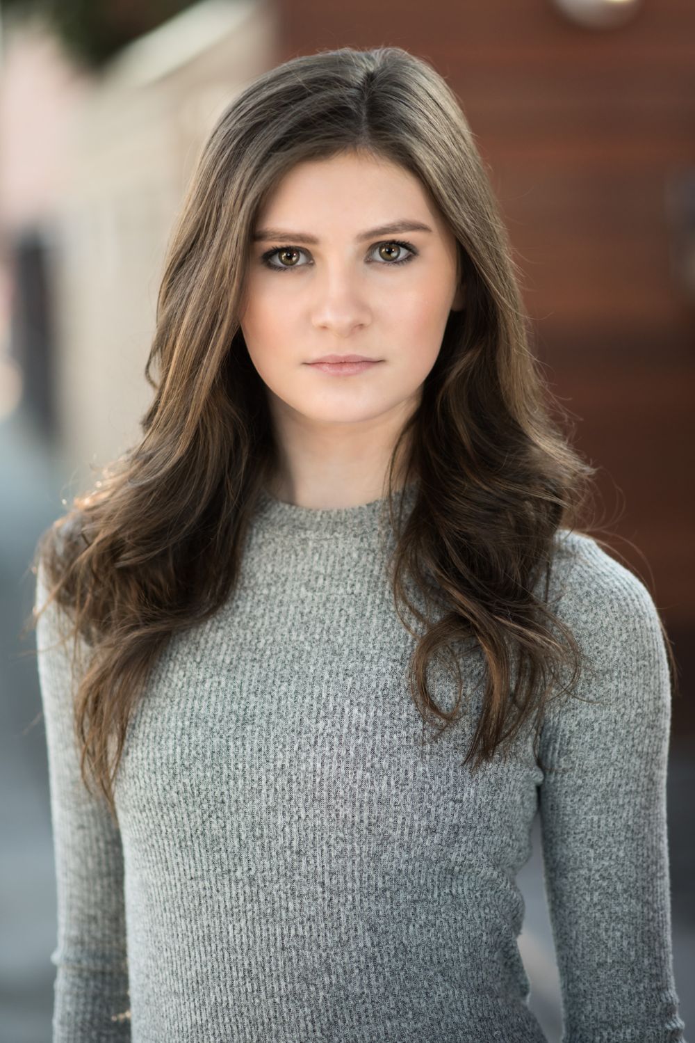 Studio portrait in a grey knit sweater with long dark wavy hair.