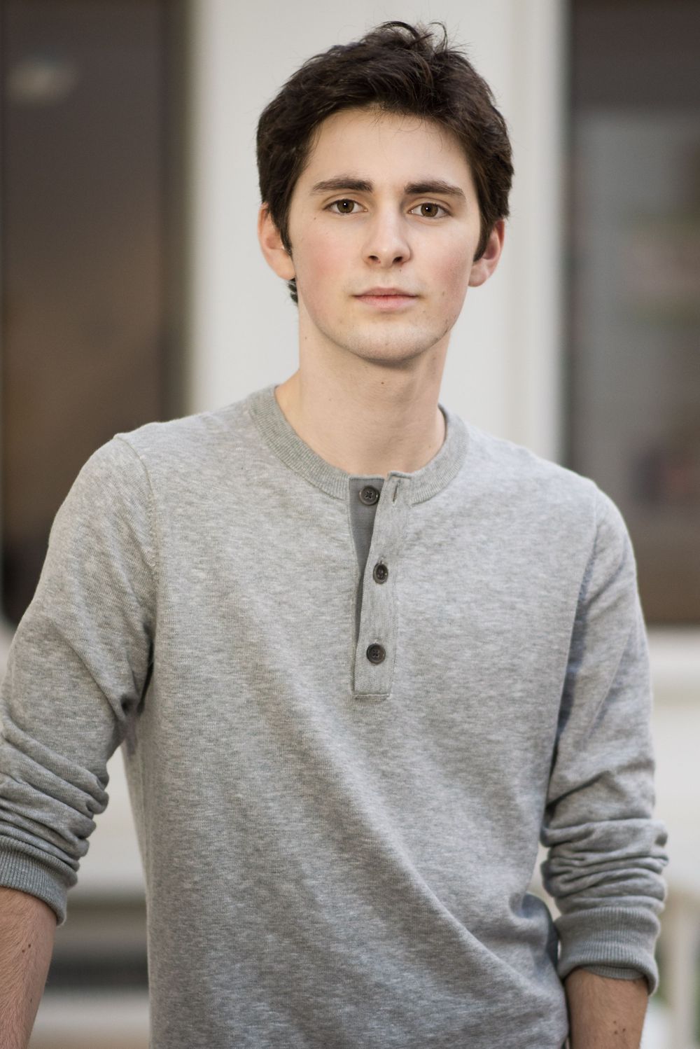 Young man wearing a casual grey henley sweater in a studio portrait.