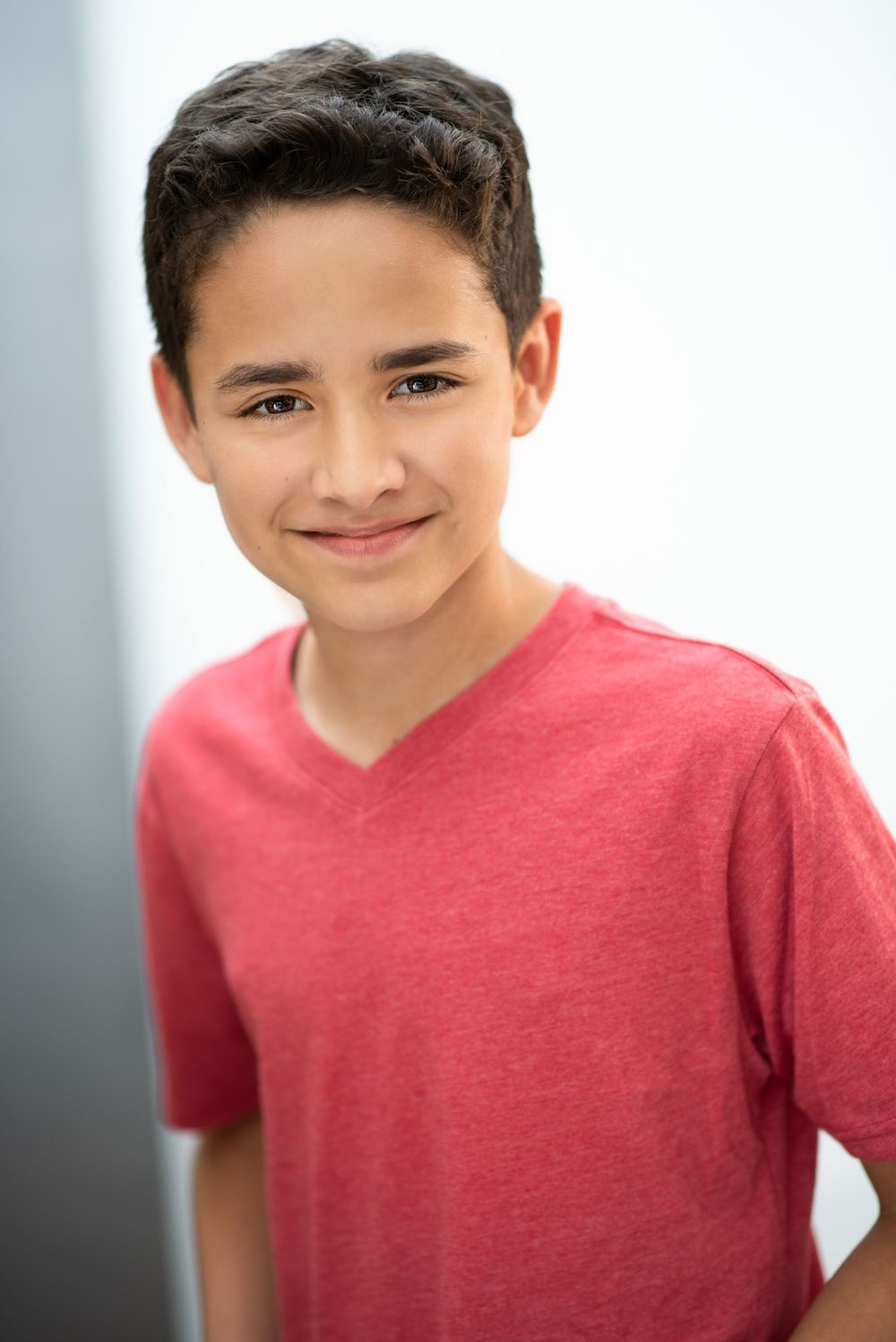 Young person wearing a v-neck red t-shirt poses for a casual portrait.