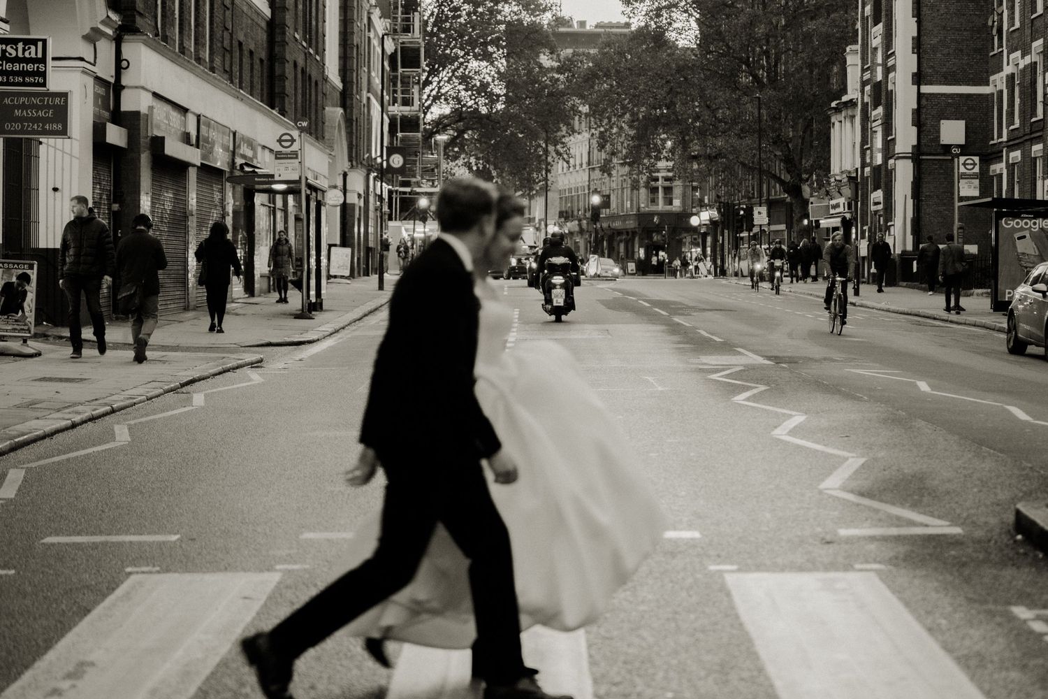 Artistic black and white photo of couple crossing city street in wedding attire. London Wedding.