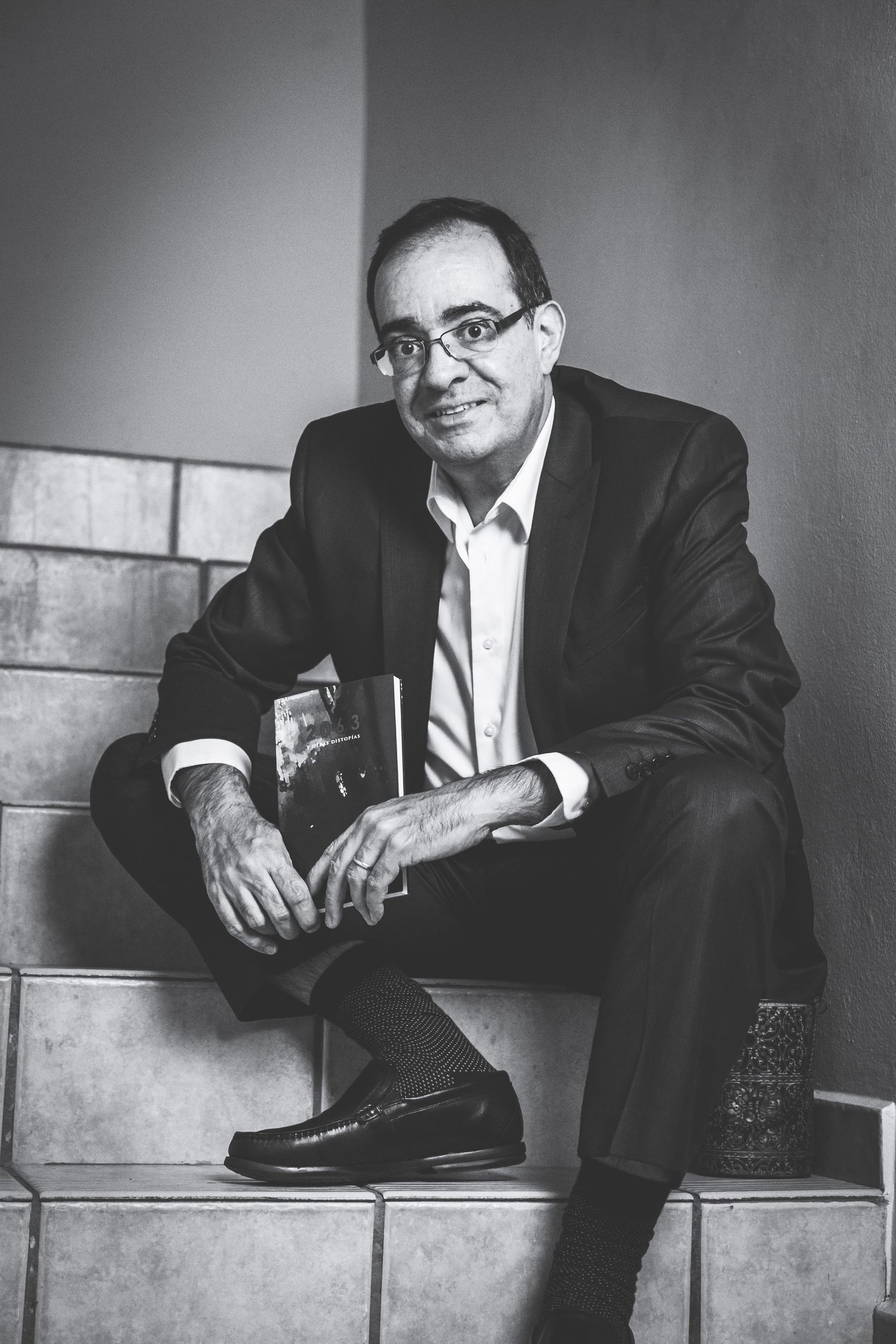 Professional in suit sits casually on tiled steps in black and white portrait.
