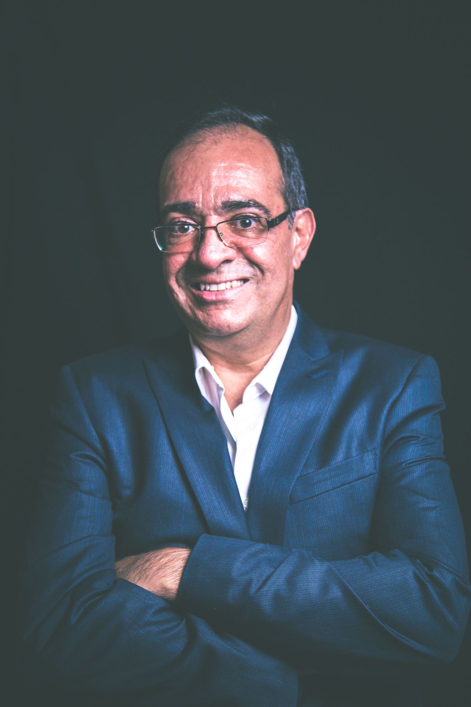 Business portrait against dark background showing warm expression.