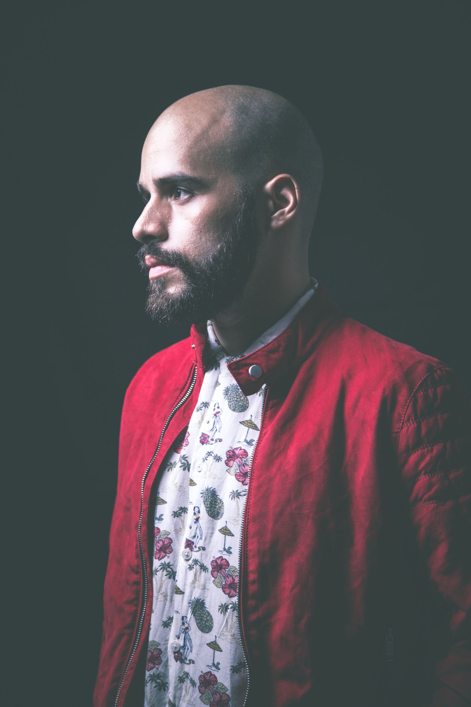 Side profile portrait of person in red jacket against dark background.