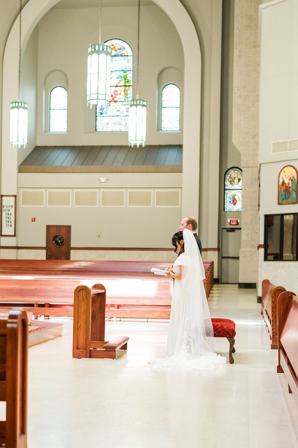 Catholic Wedding Photography at St. Monica Catholic Church, Edmond OK. Bride and groom praying during mass.