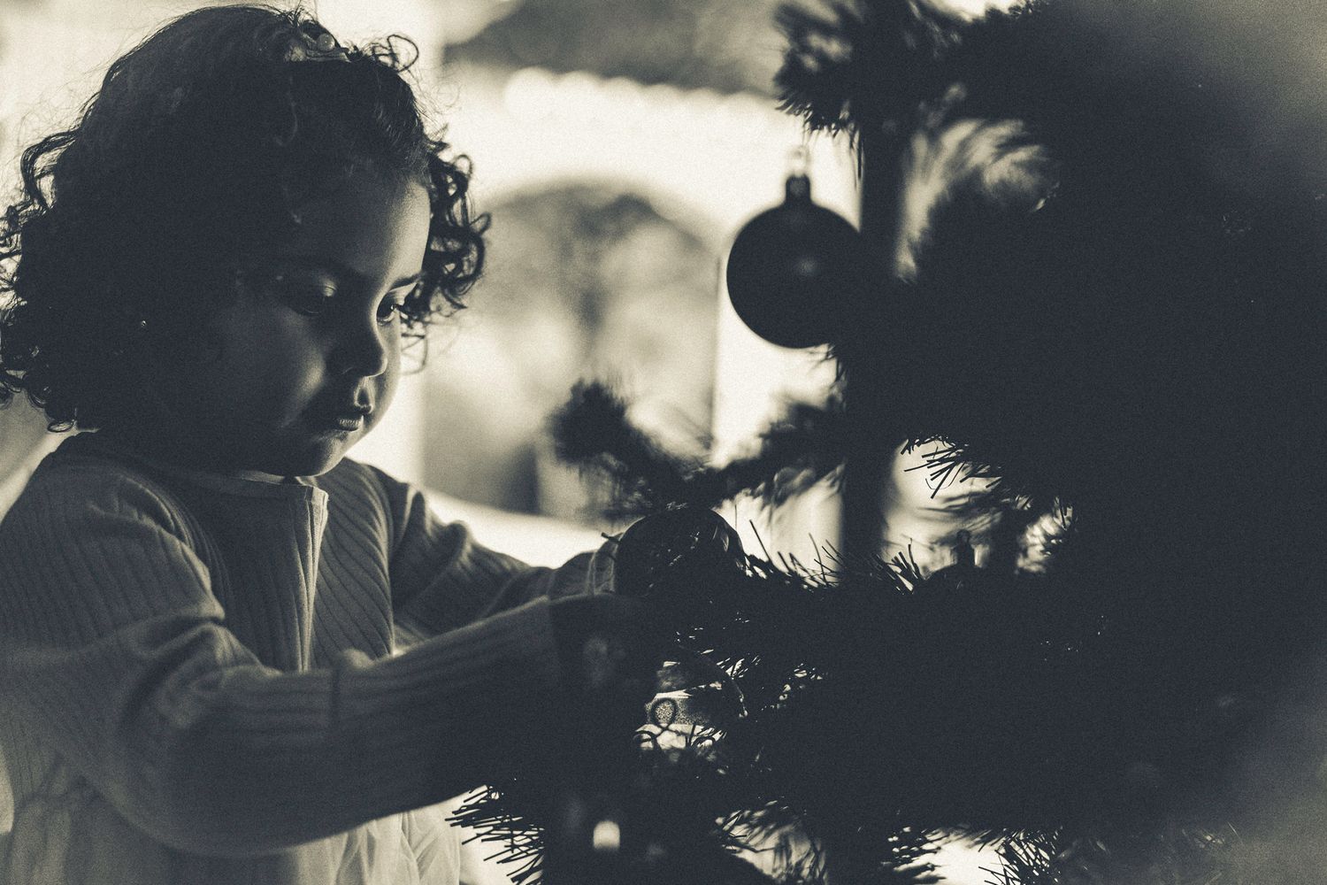 Lara is so focused while trying to tie a Christmas ball on the tree.