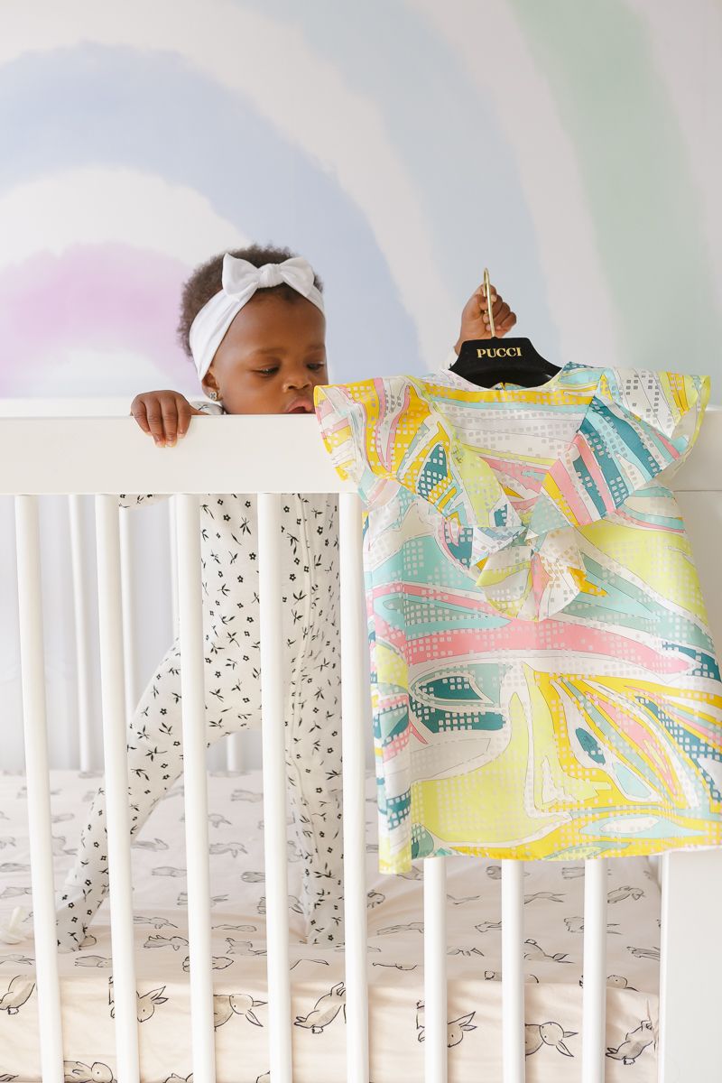 Birthday girl in crib grabbing dress by NYC family photographer Paula Ortiz