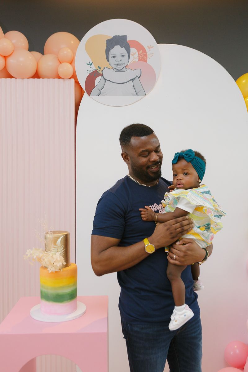 Dad holding birthday girl by cake decorations by NYC family photographer Paula Ortiz