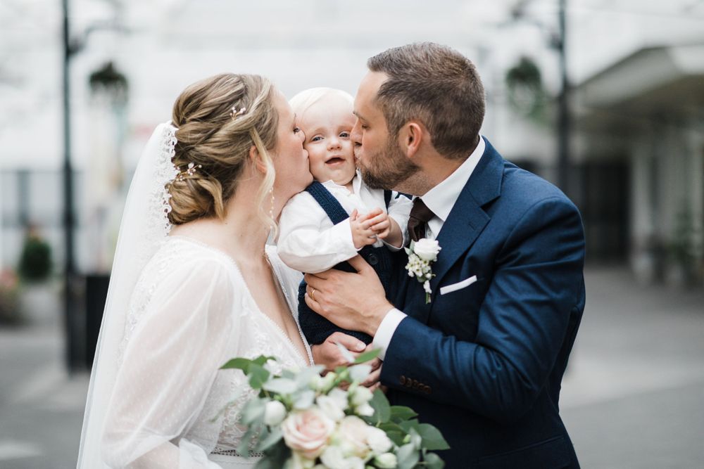 Tender family moment shared during wedding celebration against bright background.