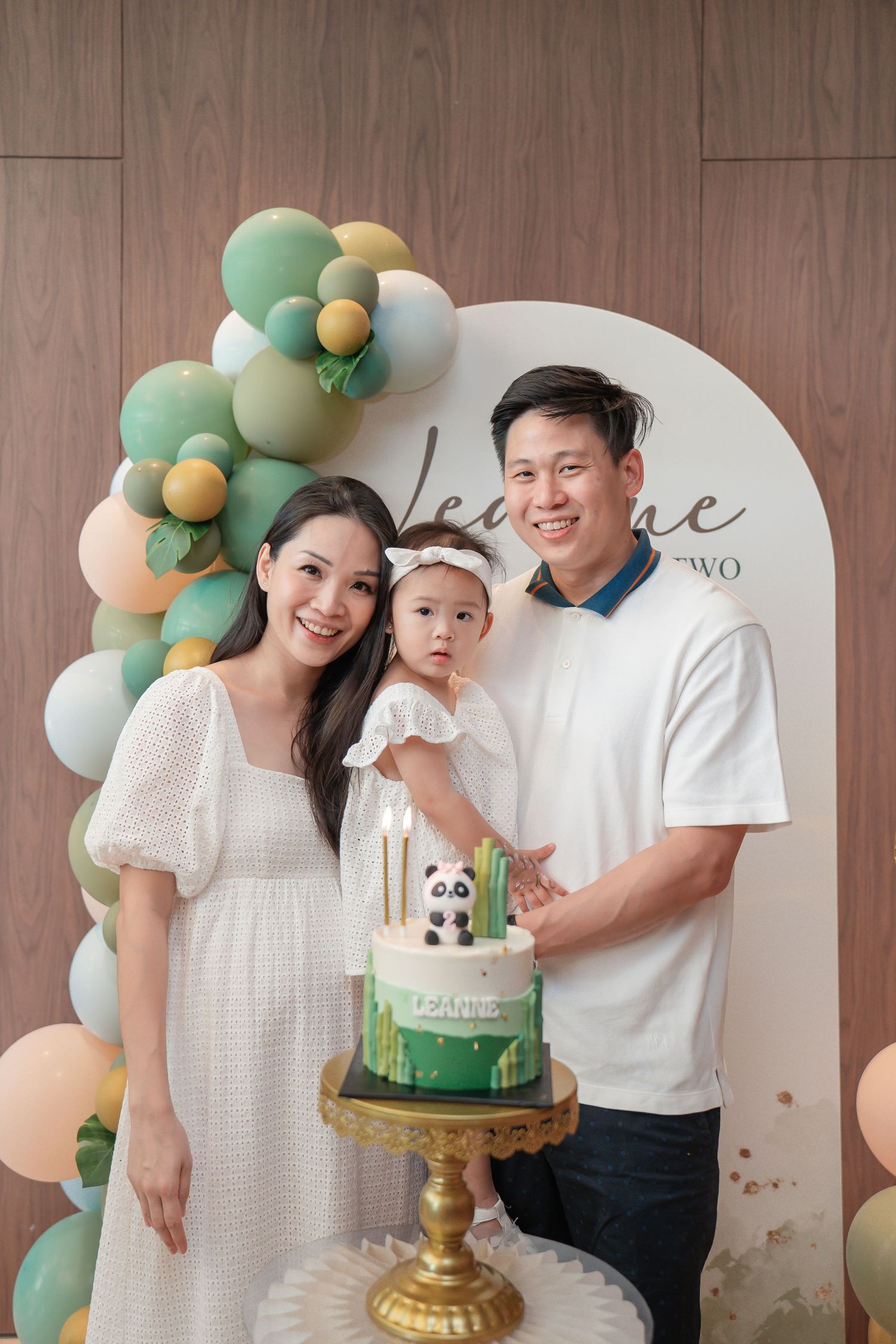 A celebration with panda-themed cake and mint green balloon arch decorations.