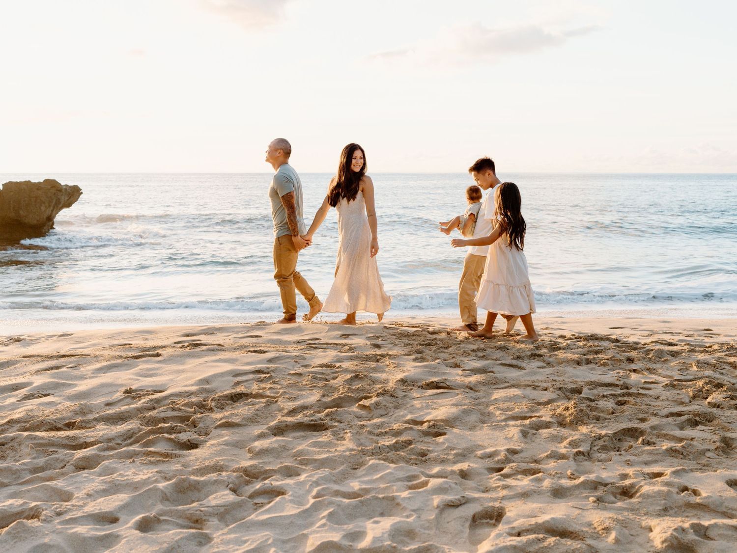 A family photoshoot with mother father and children walking on the beach Oahu in Hawaii