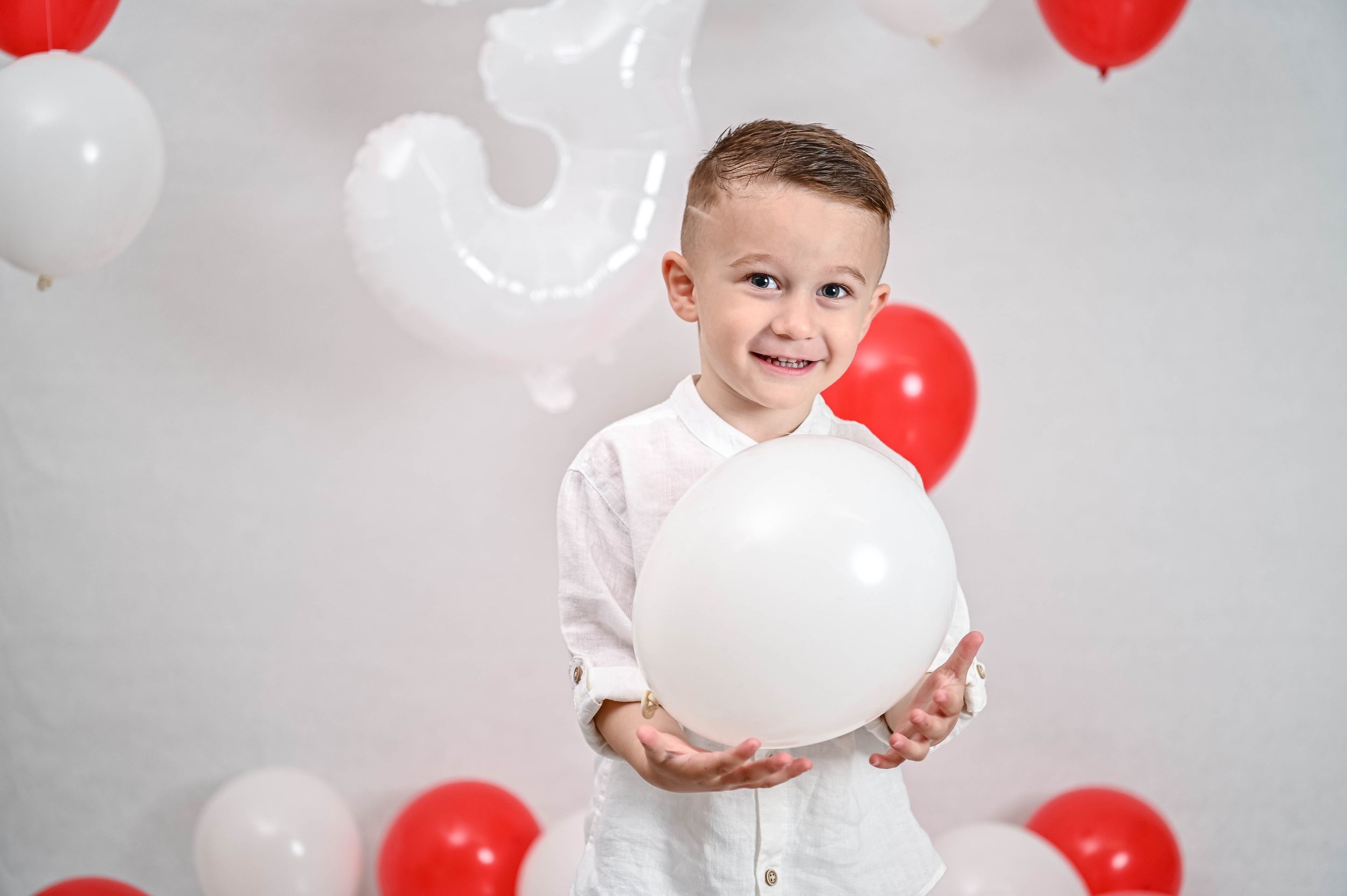 Festive photo setup with red and white balloons against light gray background.