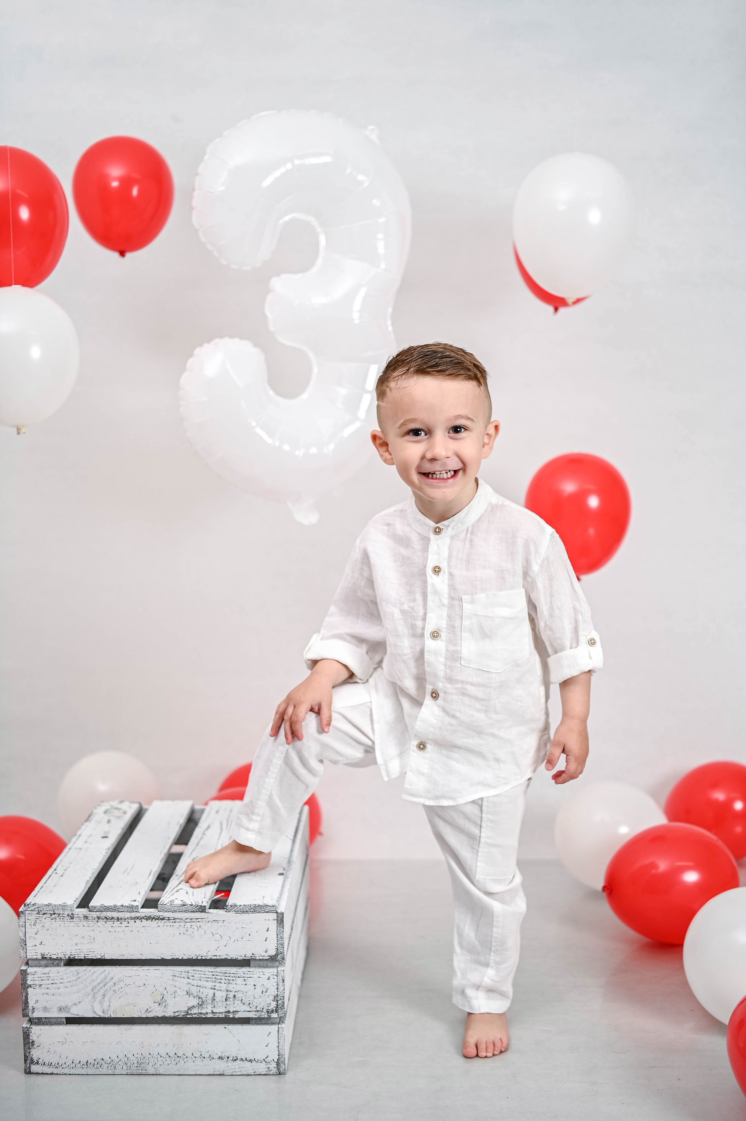 Birthday photo session with white and red balloons and distressed wooden crates.