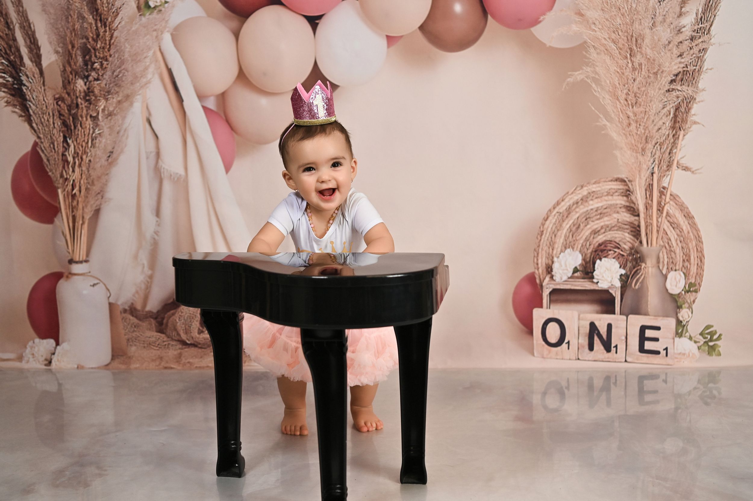 Pink balloon decorated setup with black table and ONE letter blocks display.