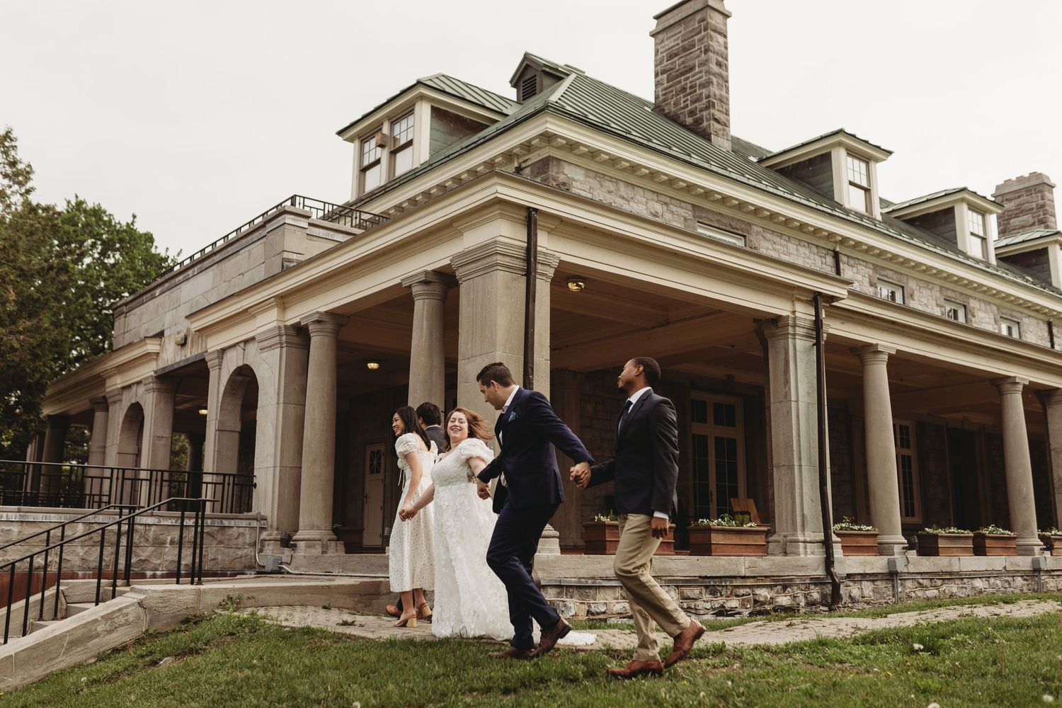 A group celebrating outside a grand historic mansion with stone columns and arches.
