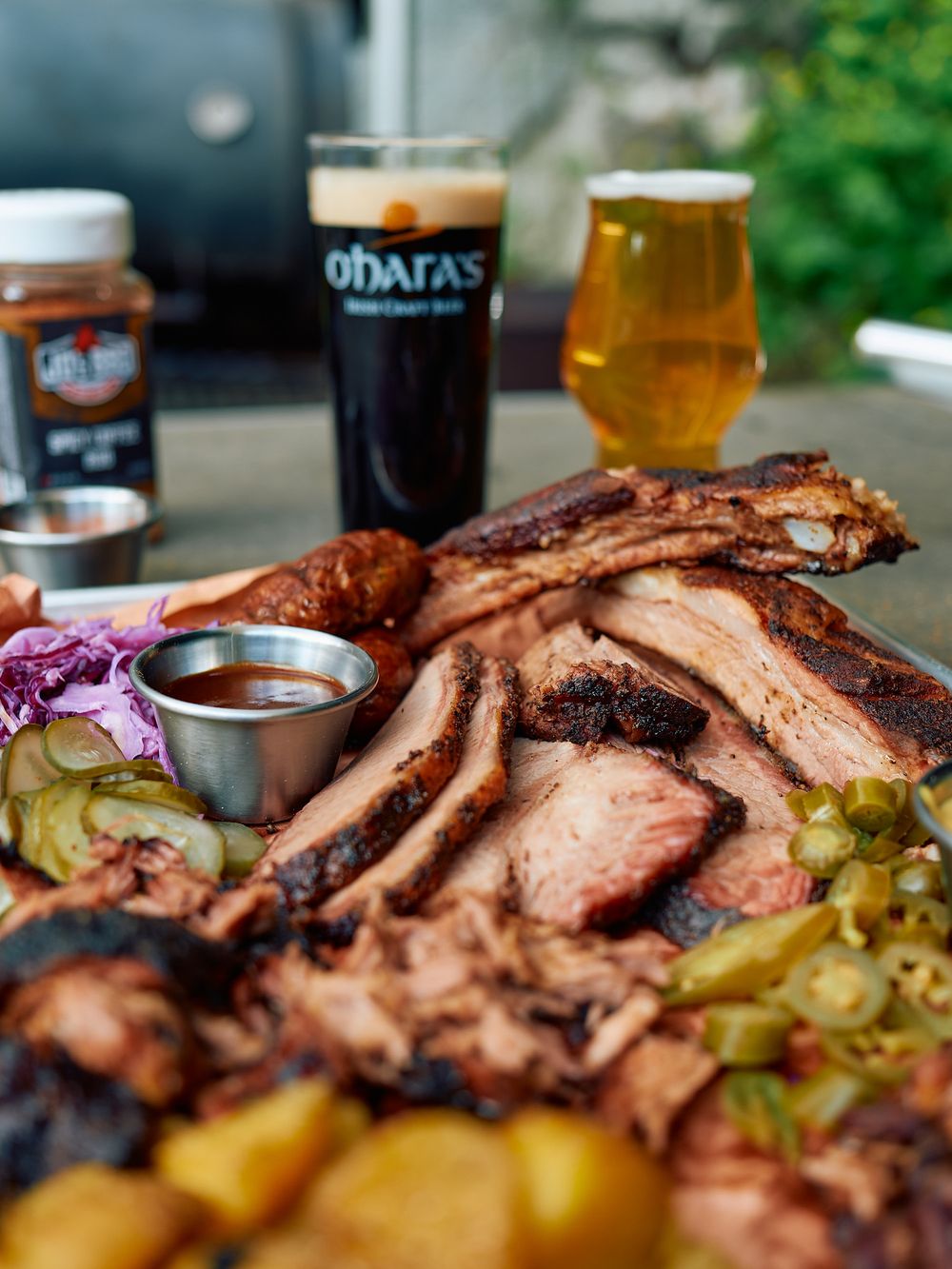 Close-up of BBQ platter with smoked meats, sides and dark beer.