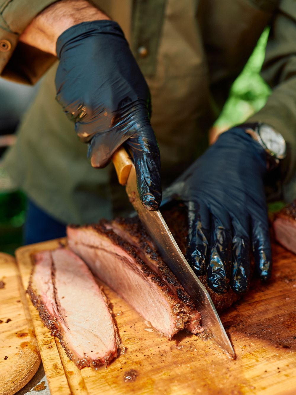 Close-up of sliced smoked brisket being cut on wooden cutting board.