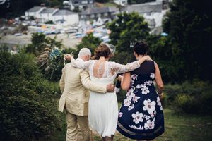 Three people walking together on a hillside during a wedding celebration.