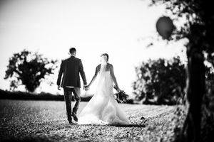 Black and white photo of a couple walking down a path together on their wedding day.