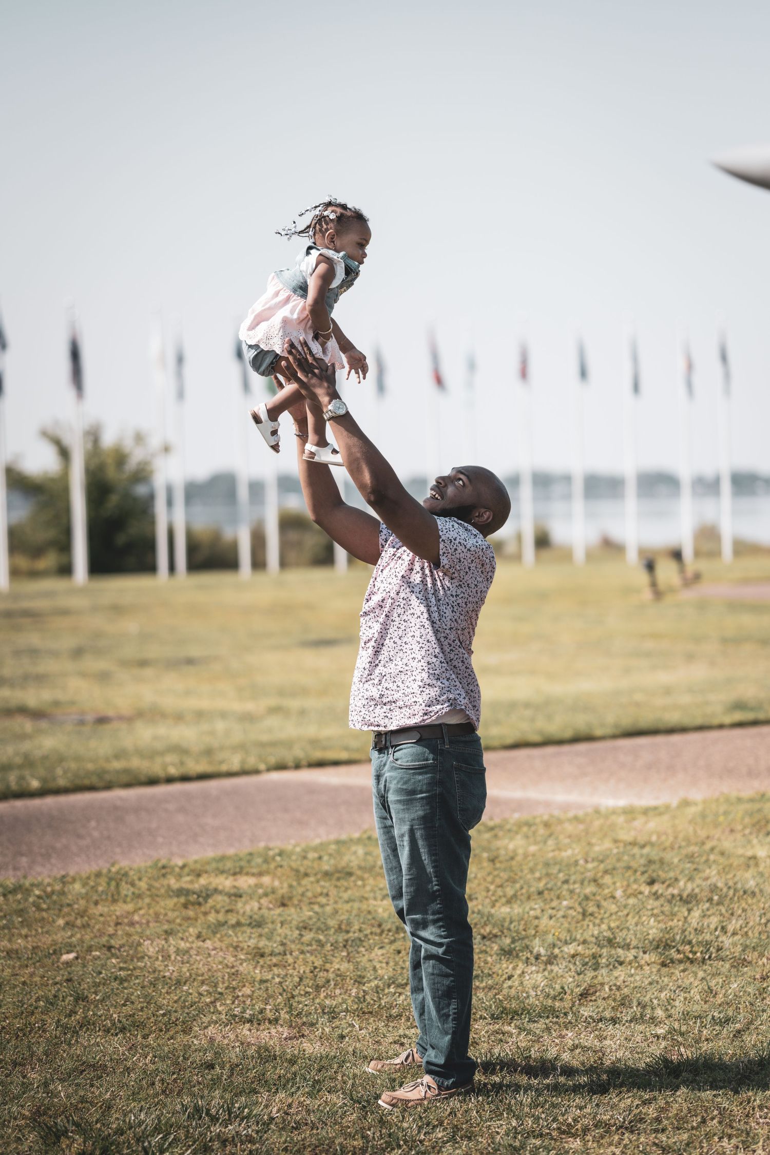A playful moment captured outdoors with flags and an aircraft display in the background.