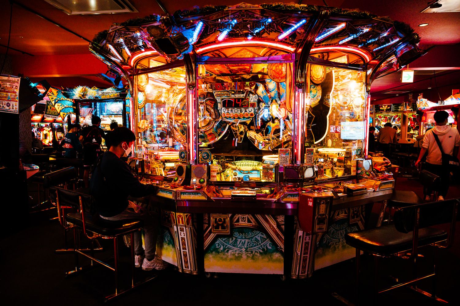 Illuminated vintage arcade game cabinet with neon lights in a dark entertainment center.