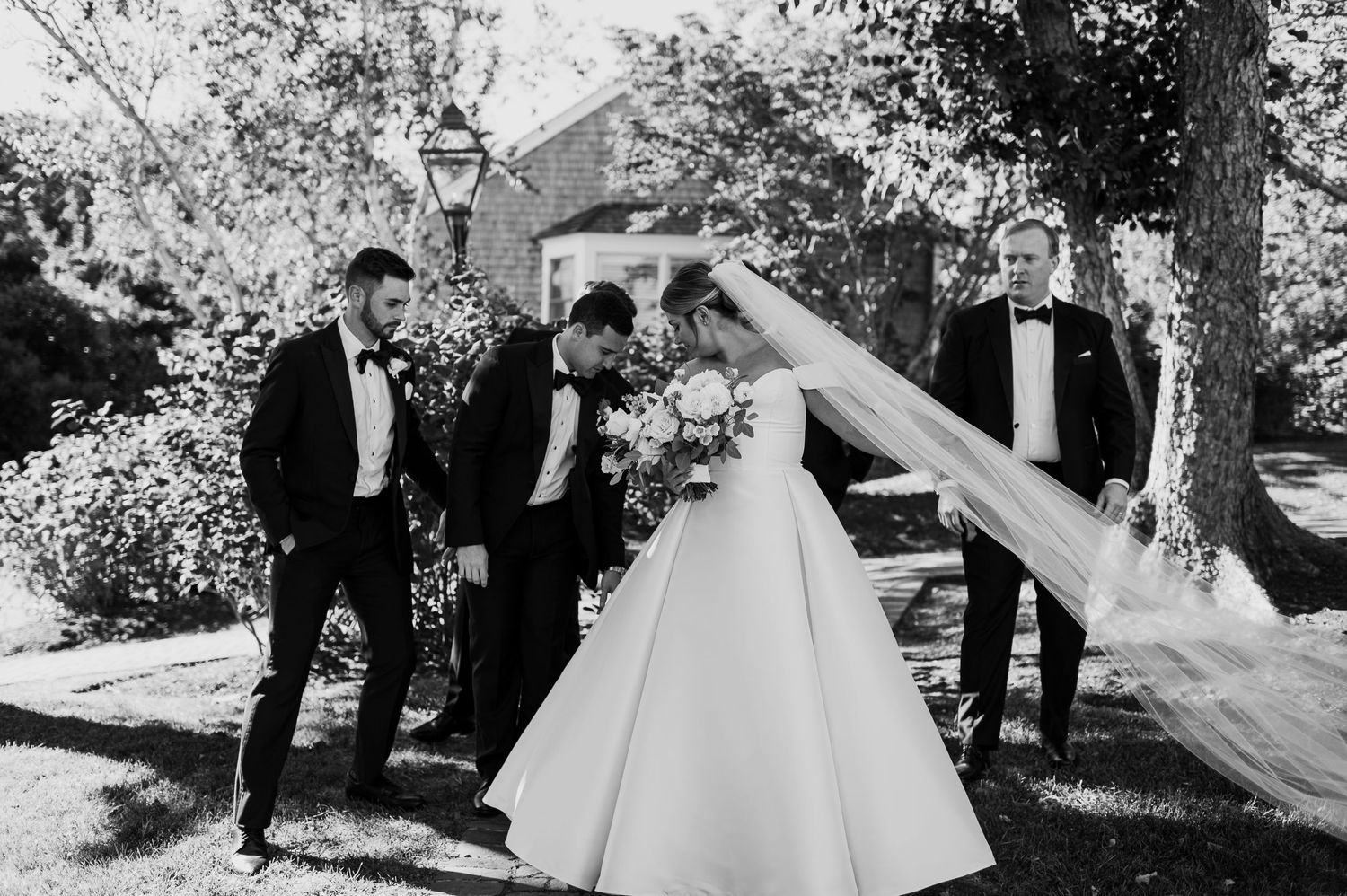 Black and white wedding party photos showing joyful moments in an outdoor garden setting.