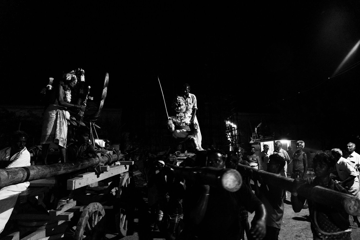 Performers stand elevated on platforms during traditional Hawaiian night ceremony.