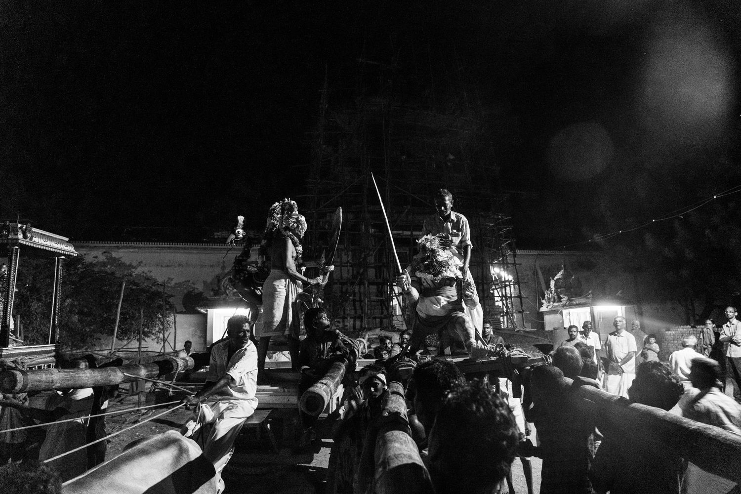 Nighttime Hawaiian performance featuring elevated performers with traditional implements.