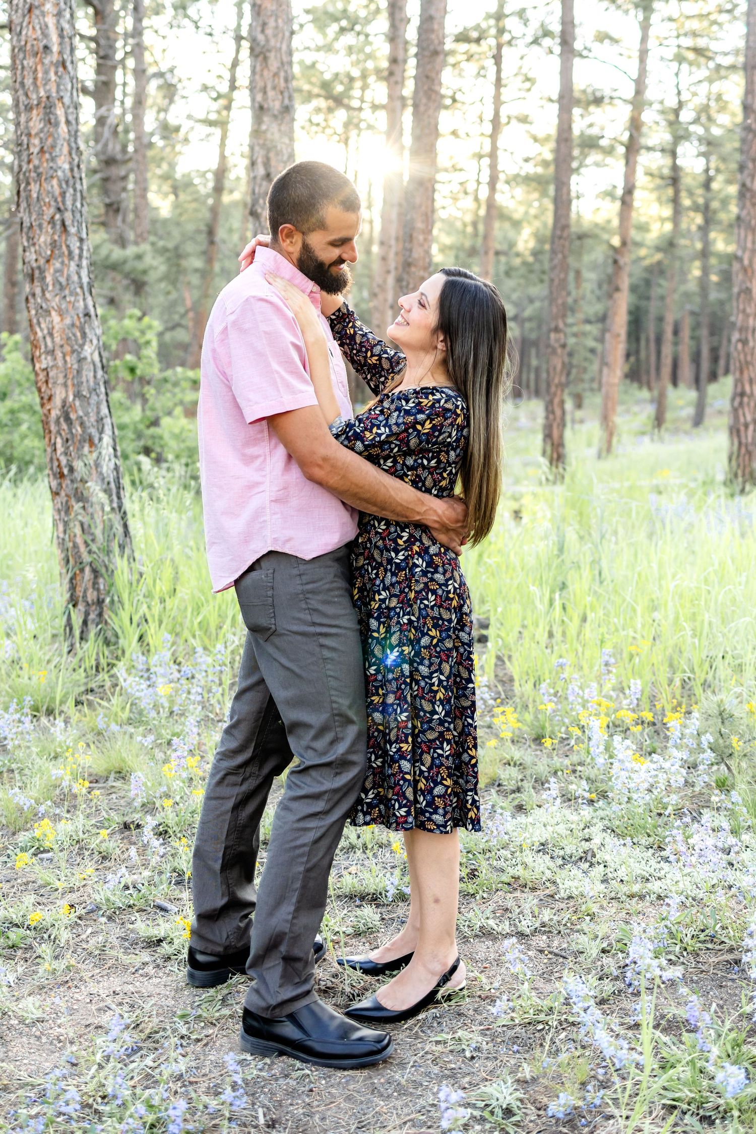 Mom and dad stand and smile at one another at sunset during their family session in Colorado Springs.