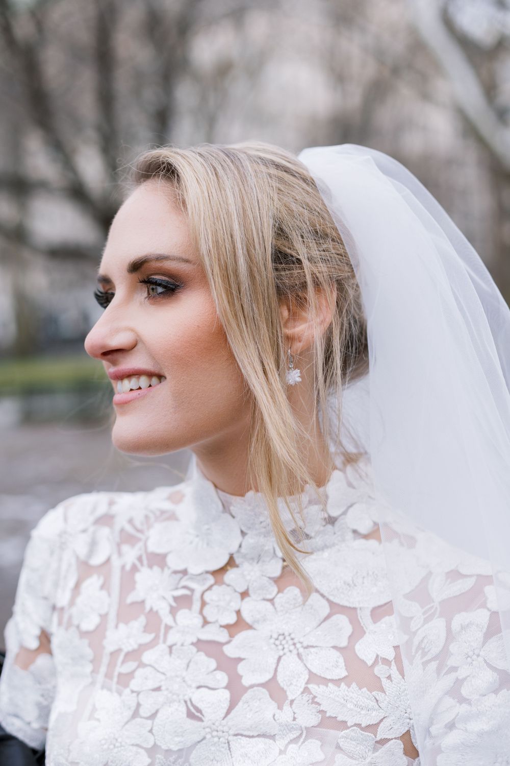 Joyful close-up bridal portrait showing delicate lace neckline and veil details.